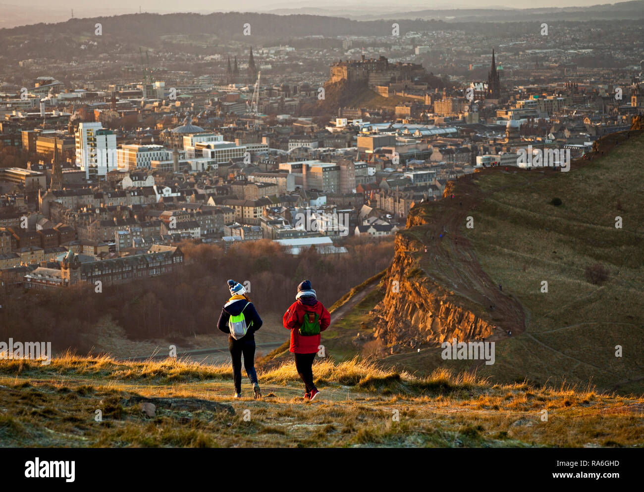Edinburgh, Scotland, UK. 2nd January 2019. UK weather, tourists enjoy the view from Arthur's seat summit in Holyrood Park just around sunset looking over Salisbury Crags, although the temperature is minus 1 degree after a night of minus six degrees. Stock Photo