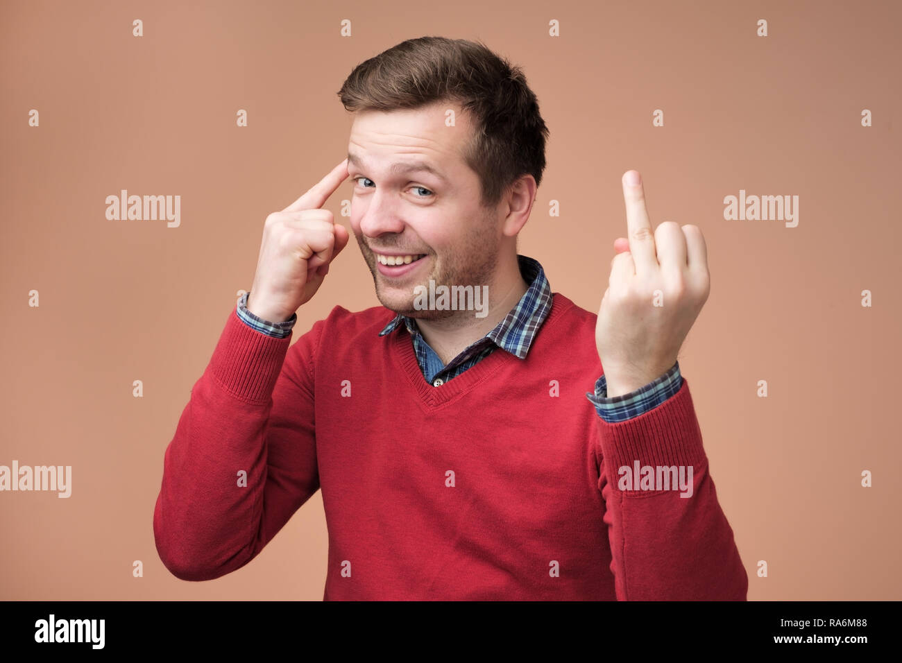 Caucasian smiling man in red sweater showing his finger without marriage ring Stock Photo