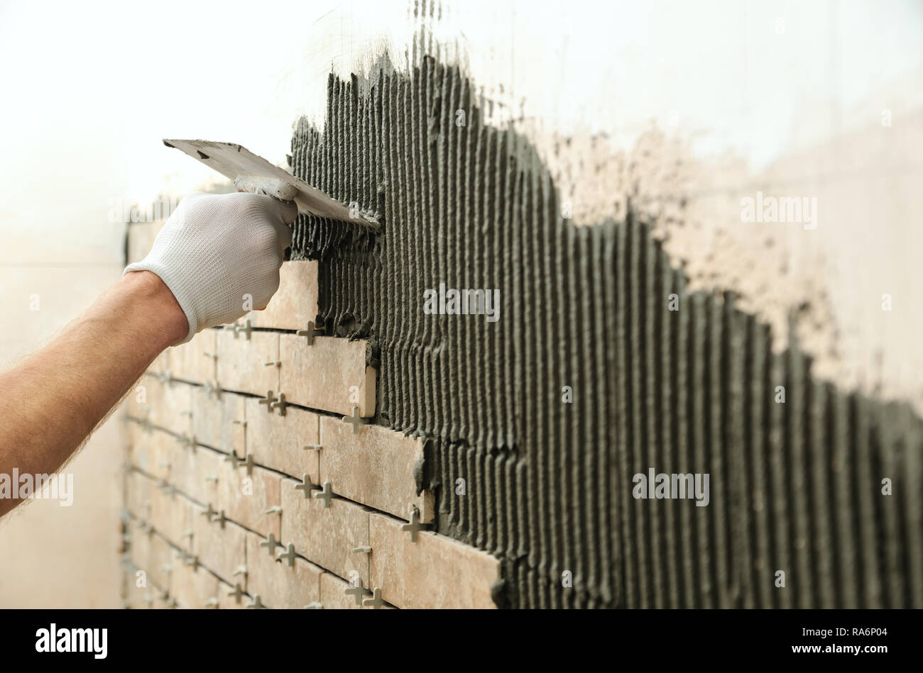 Installing the tiles on the wall. A worker setting tiles in the form of