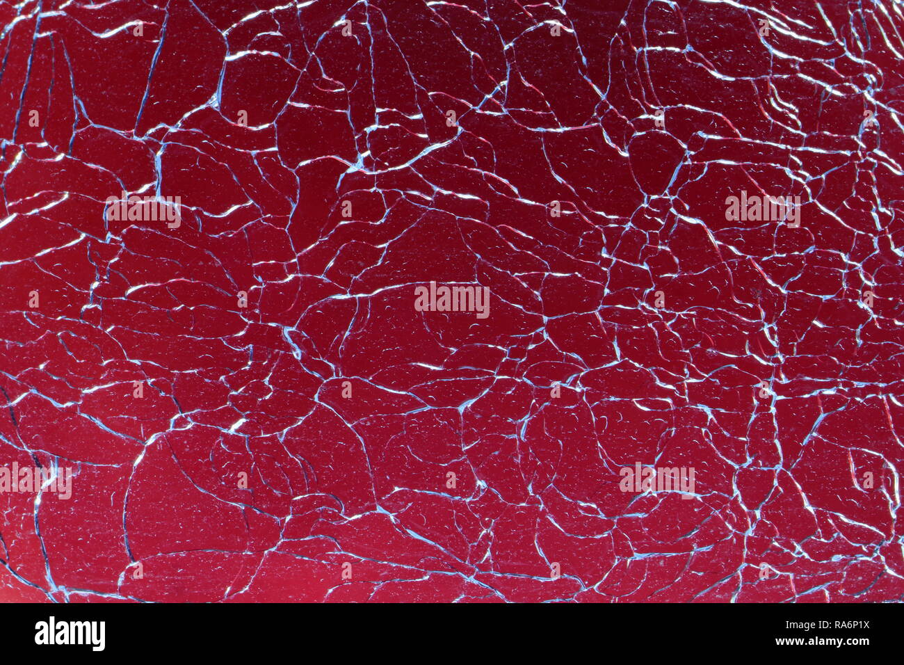 Abstract broken glass design background. Cracked, shattered glass against red background. Stock Photo