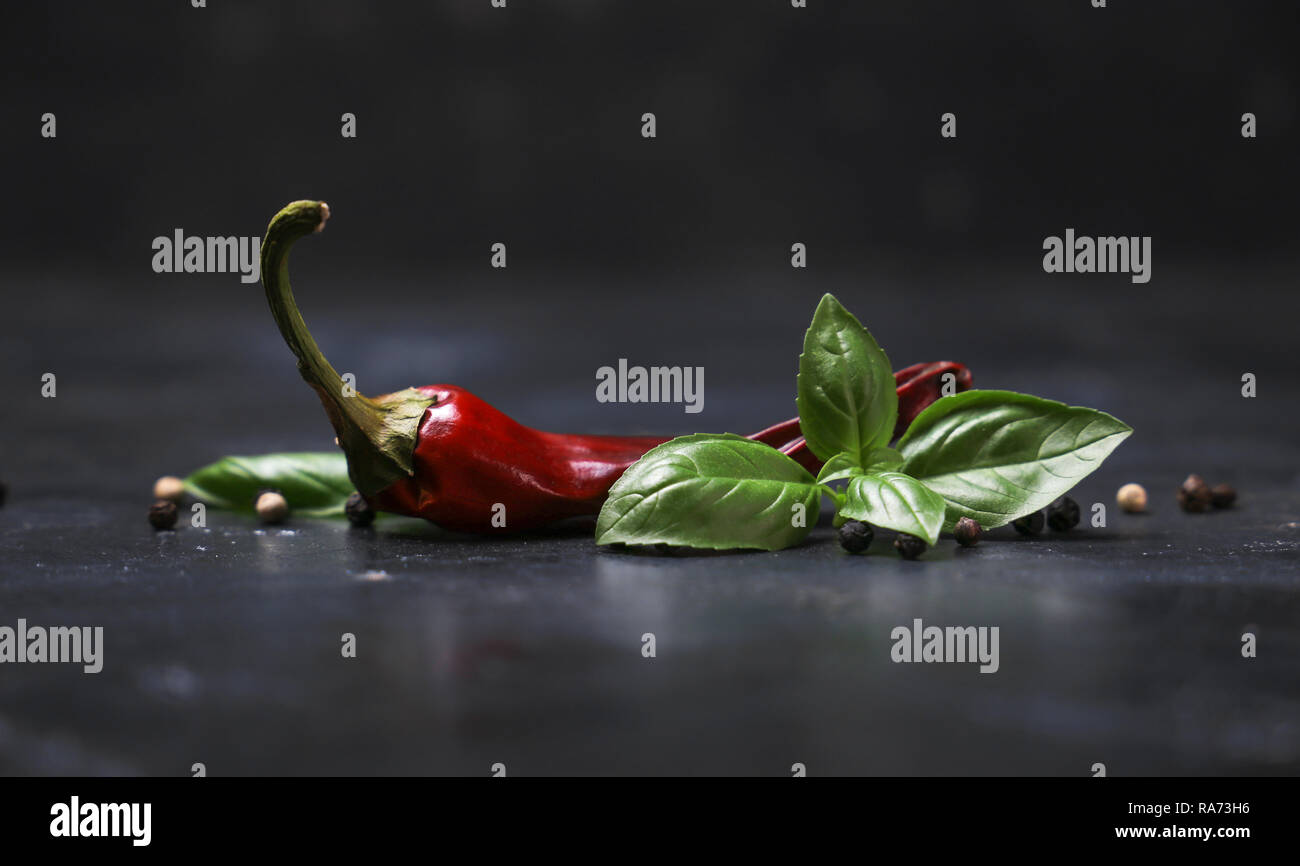 chili peppers with basil and peppercorns on a rustic surface Stock Photo Alamy