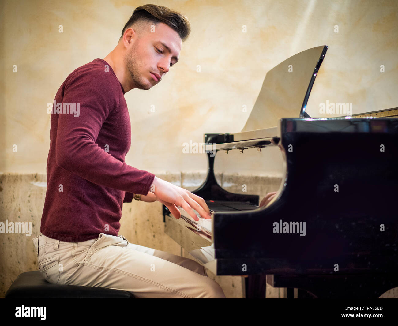 Young handsome male artist playing classical piano Stock Photo