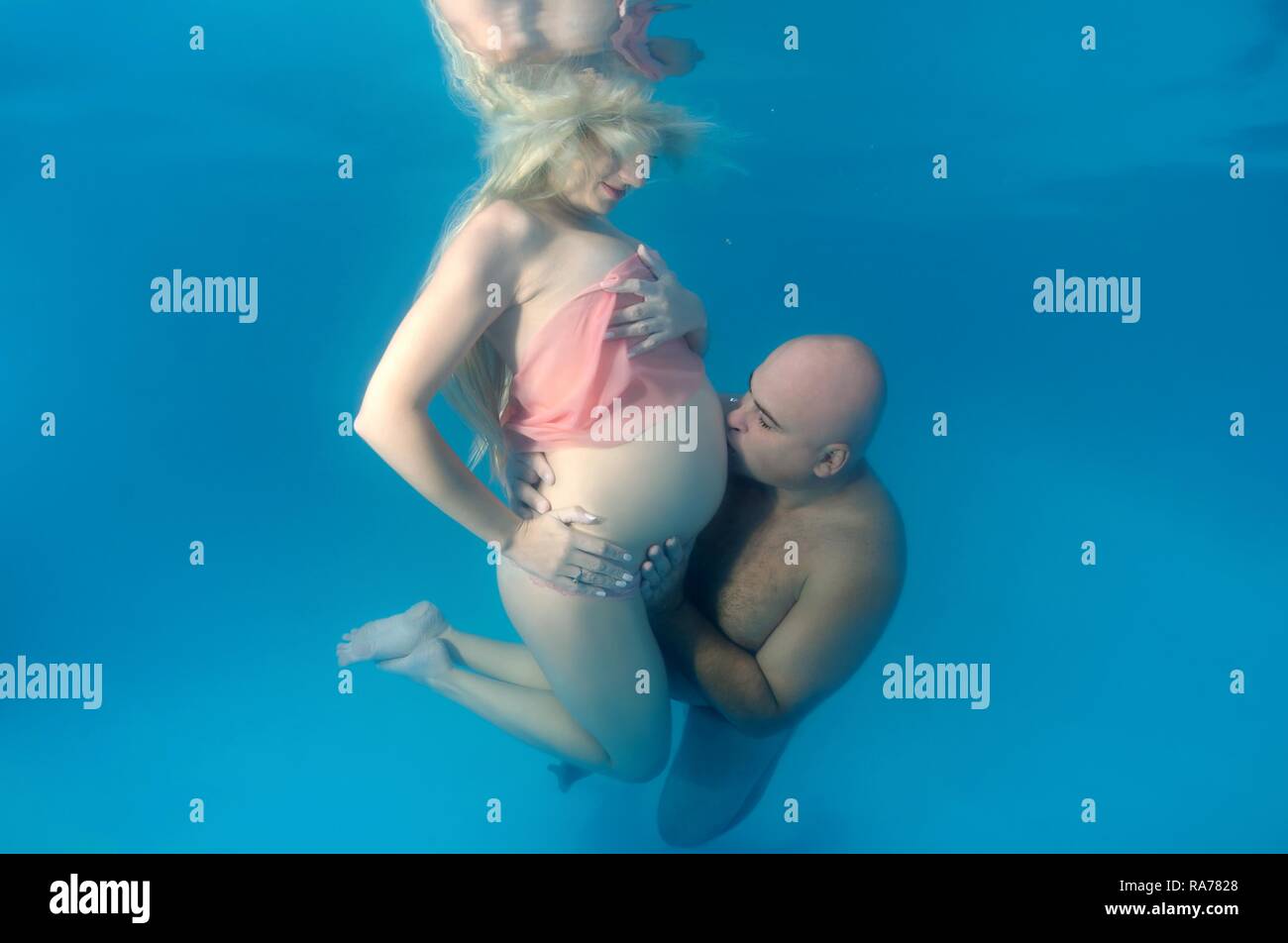 Pregnant woman and man, underwater fashion in a pool Stock Photo