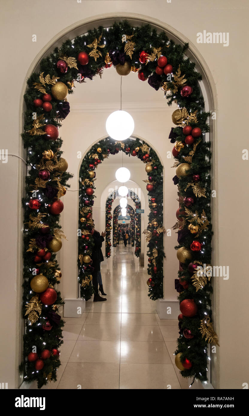 Diminishing perspective of a series of arches decorated with Christmas greenery and decorations in green, gold and red in Somerset House, central Lond Stock Photo