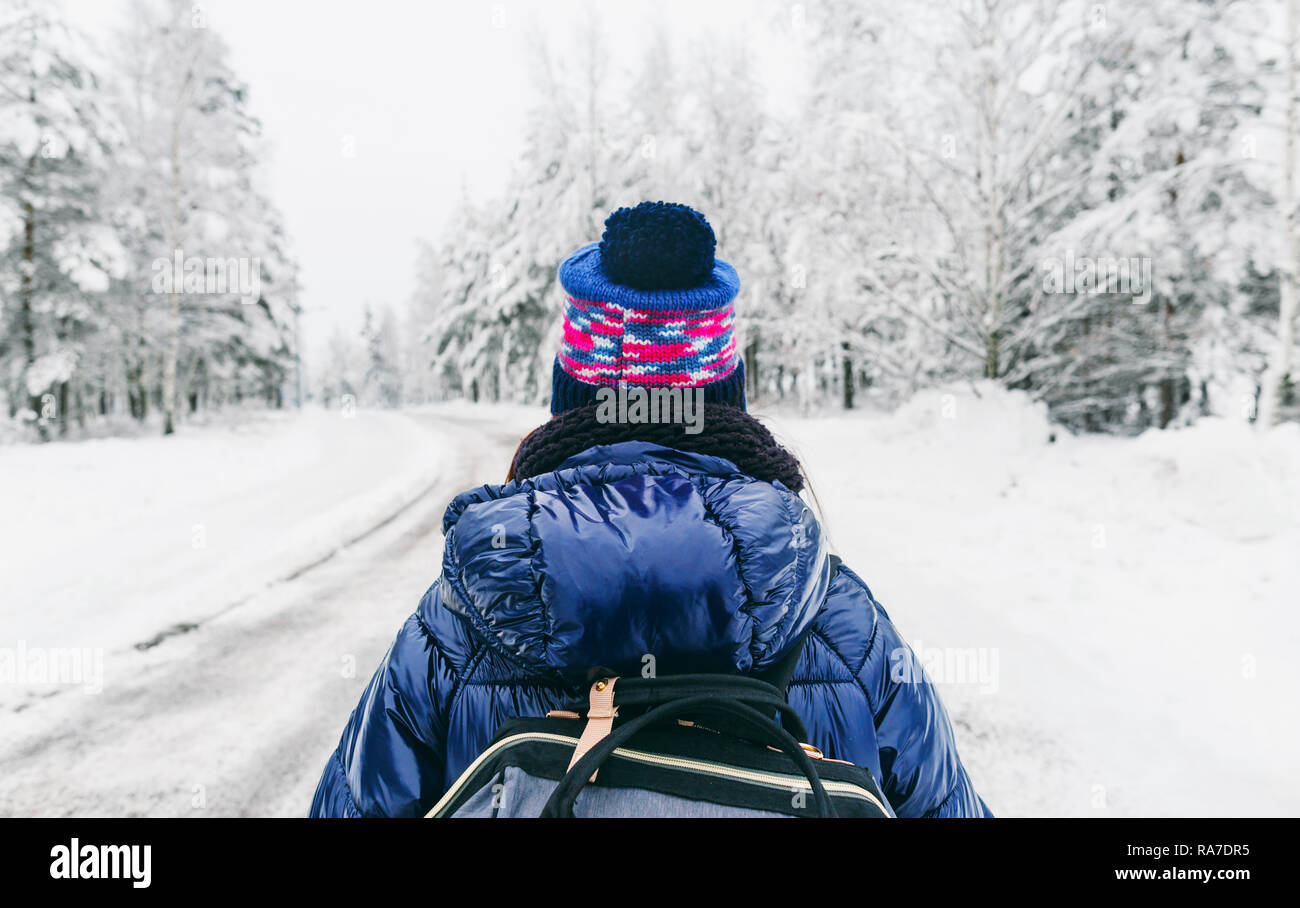 Travel Lifestyle. Young woman with backpack in the winter on snowy road in Sweden Stock Photo