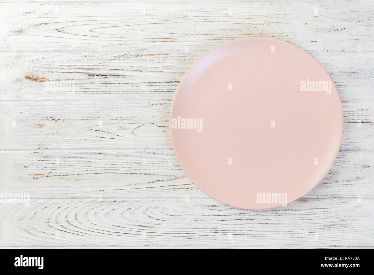 Directy above Empty pink matte plate on white wooden background with ...