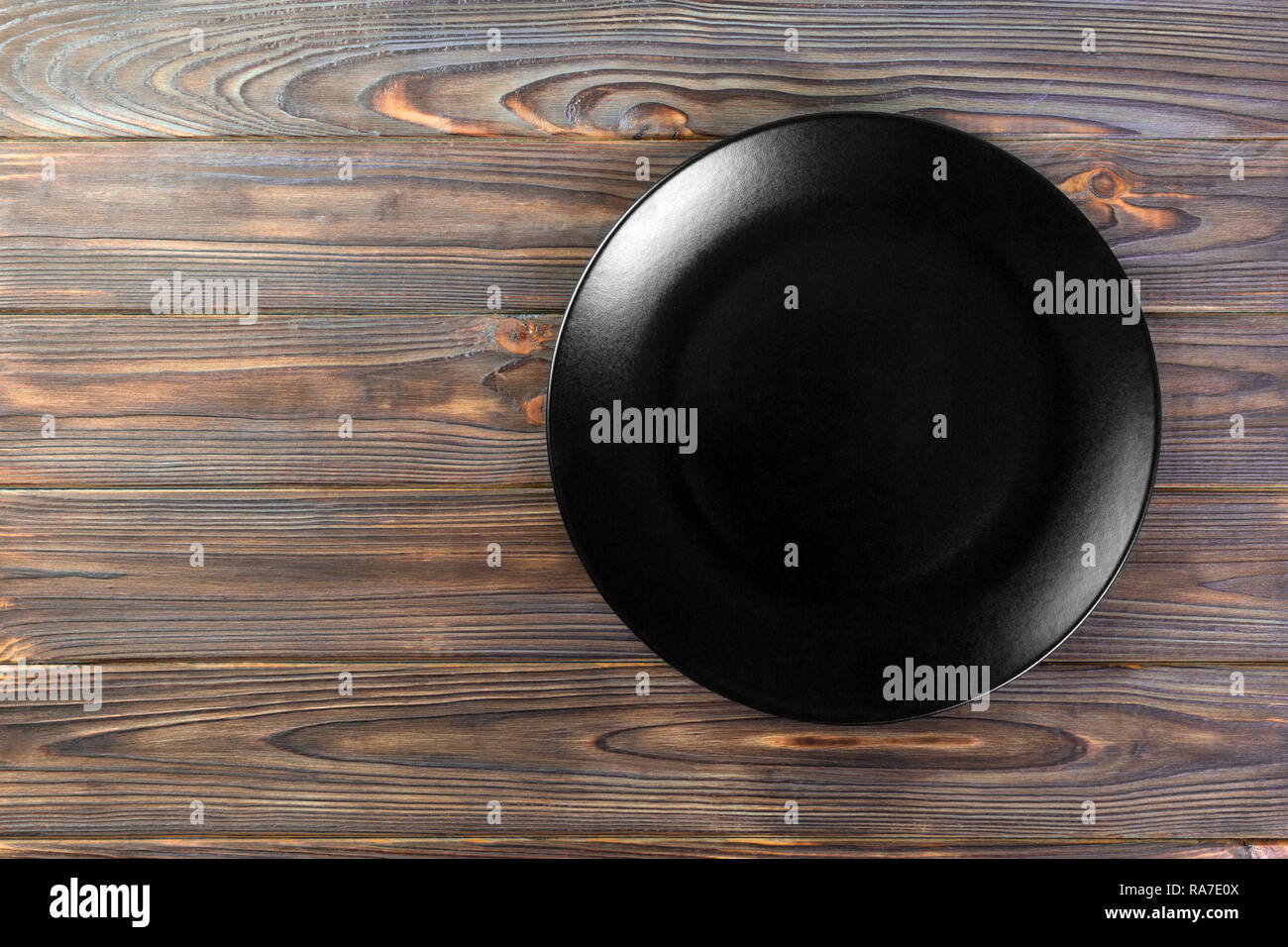 Directy above Empty black matte dish for dinner on wooden background ...