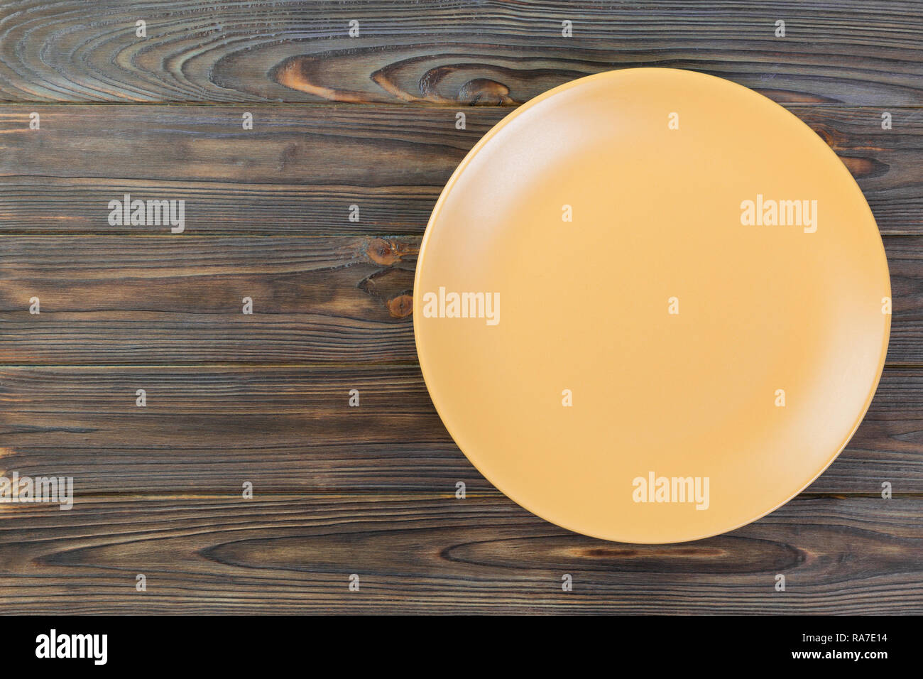 Directy above Empty yellow matte dish for dinner on dark wooden ...