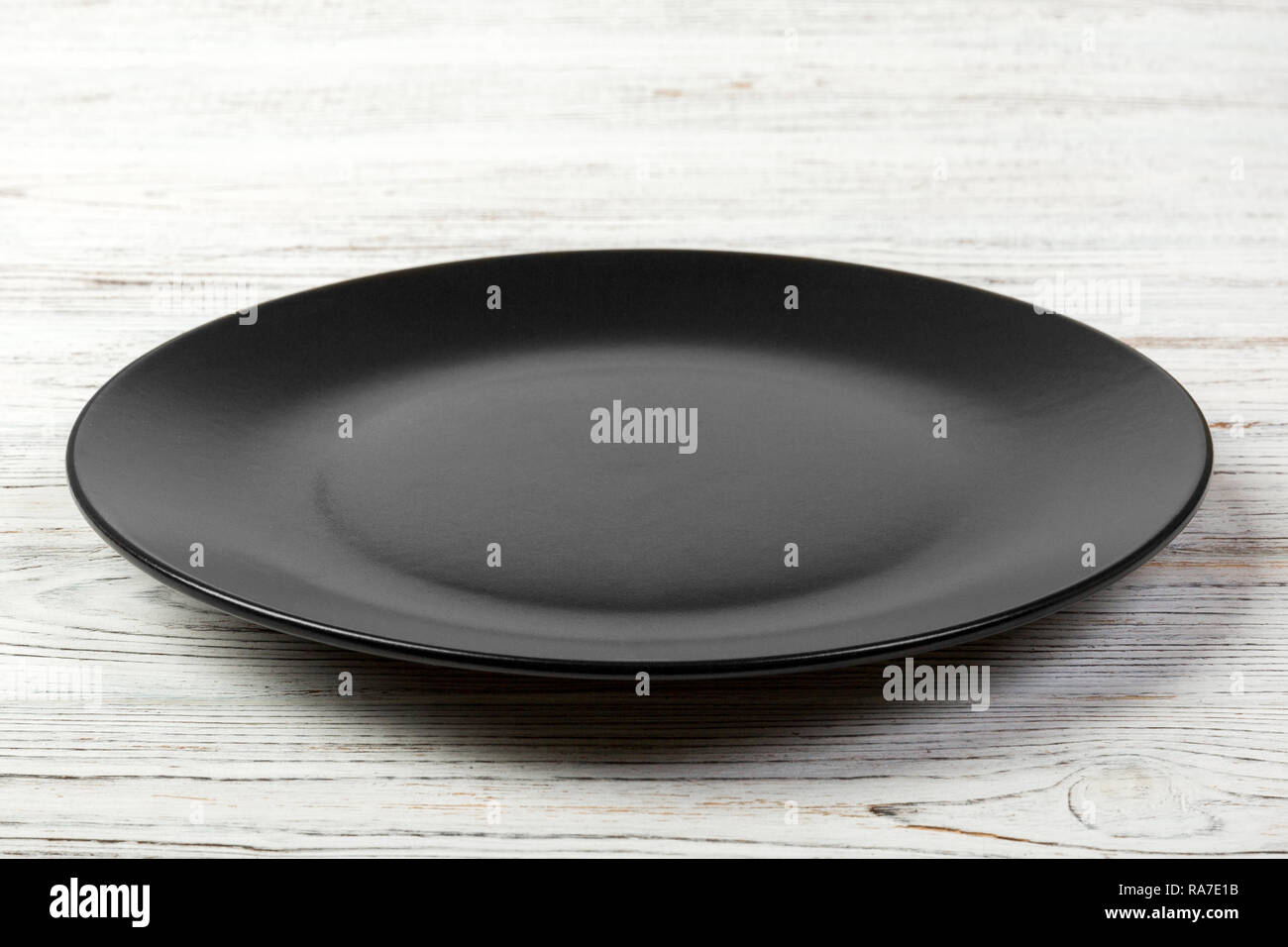 Perspective view. Empty dark matte dish for dinner on white wooden ...