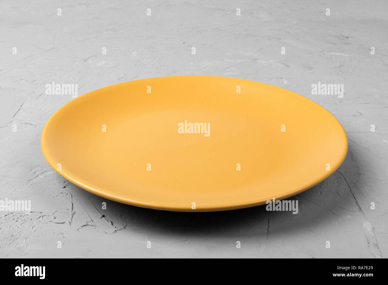 Top view of matte round empty orange plate on dark cement background ...