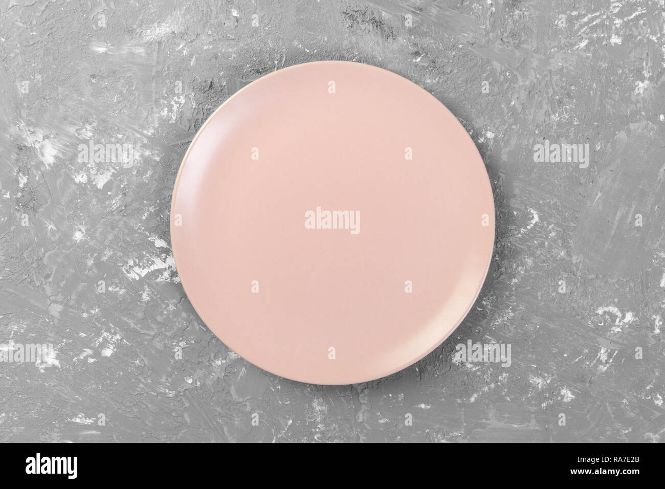 Top view of matte round empty pink plate on dark cement background ...