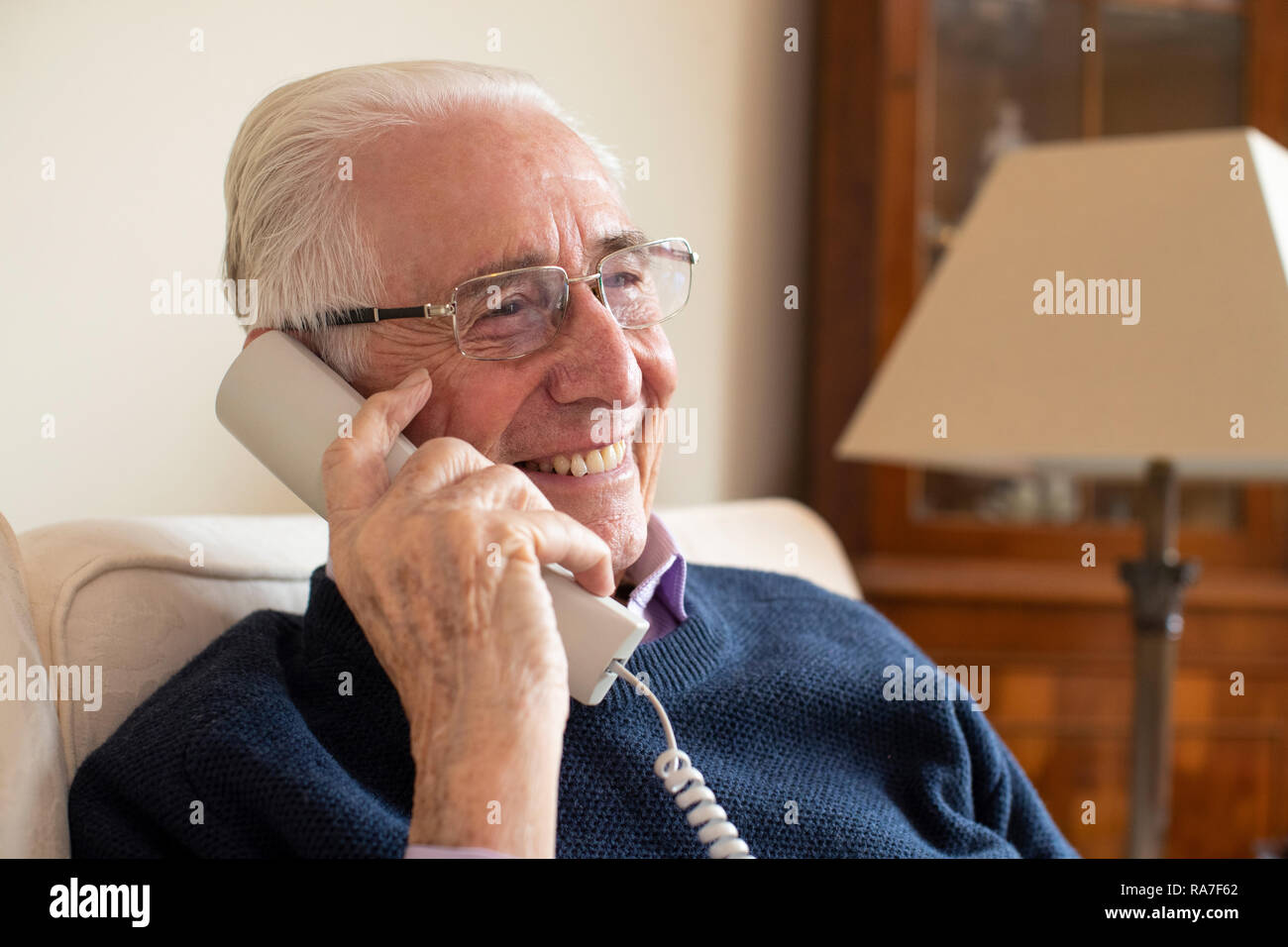 Smiling Senior Man Using Phone At Home Stock Photo