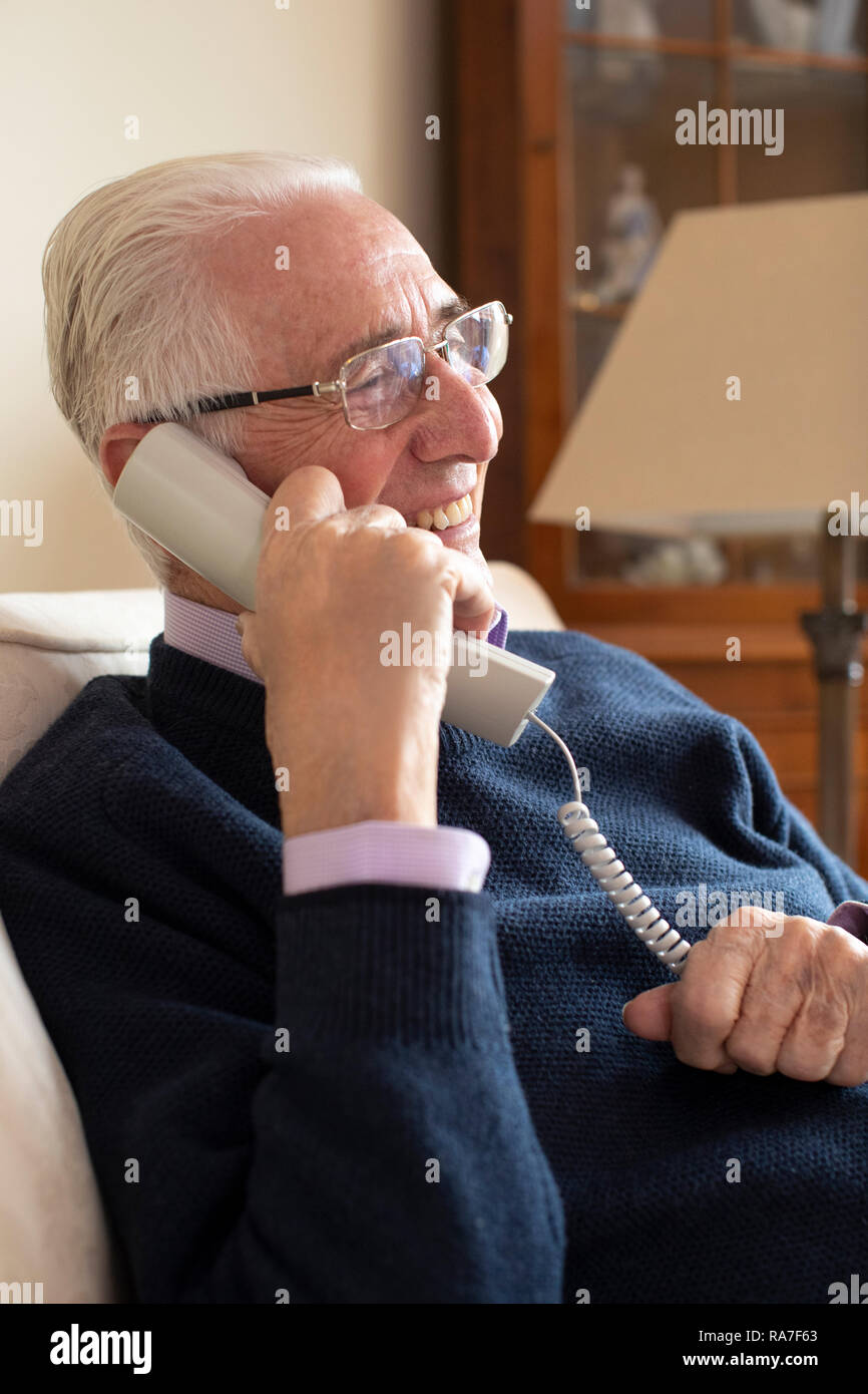 Smiling Senior Man Using Phone At Home Stock Photo