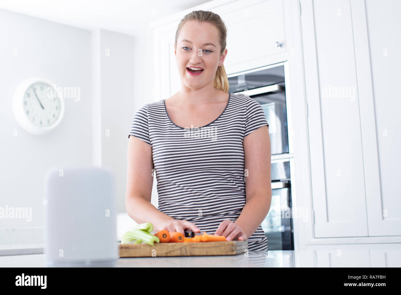 Woman Preparing Food At Home Asking Digital Assistant Question Stock Photo