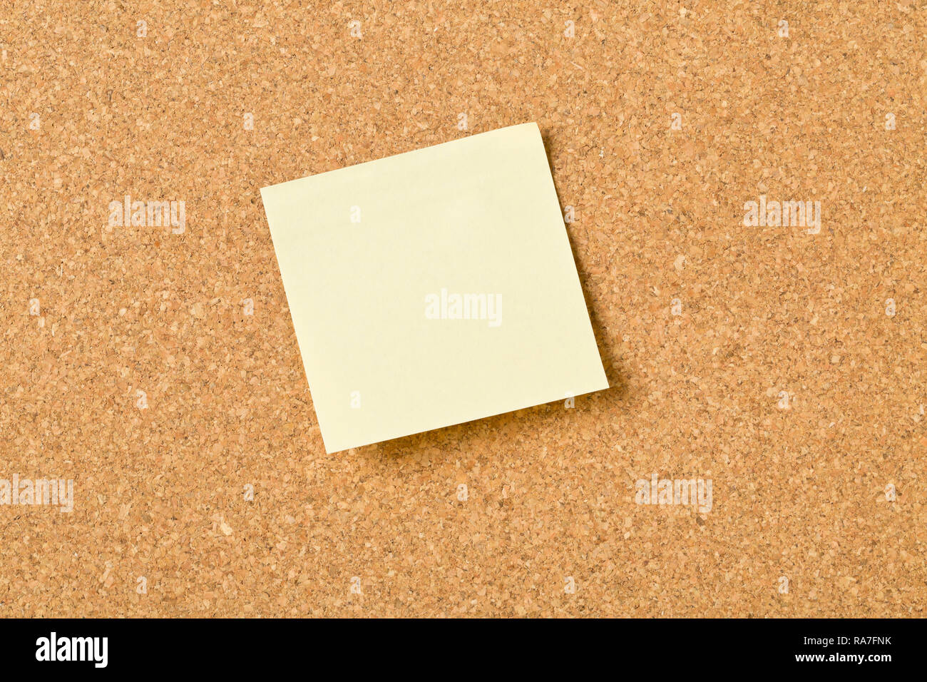 Empty yellow sticky paper memo note on cork board with copy space Stock Photo