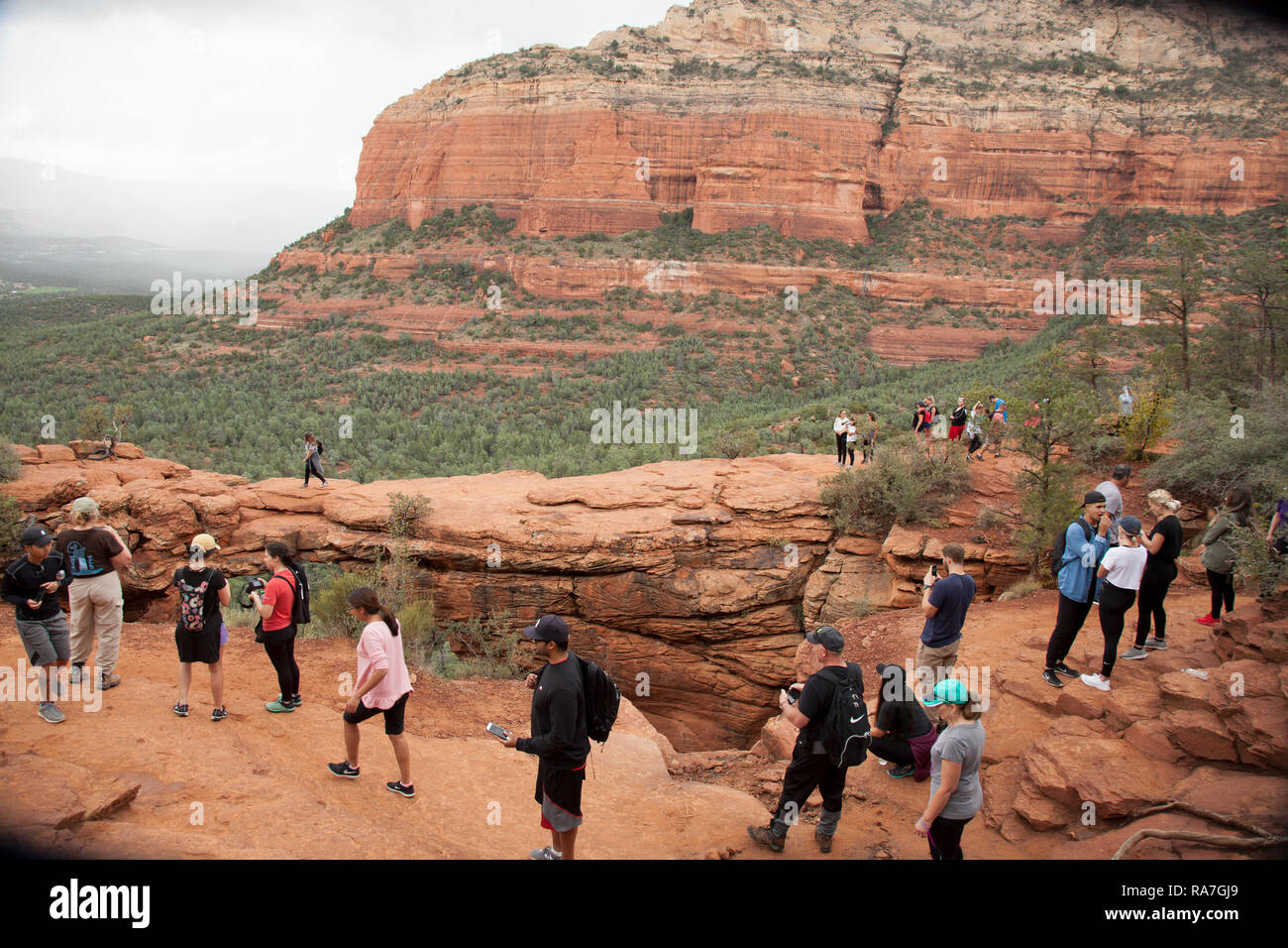 people waiting in line to walk across Devils Bridge a natural rock arch formation in Sedona Arizona Stock Photo