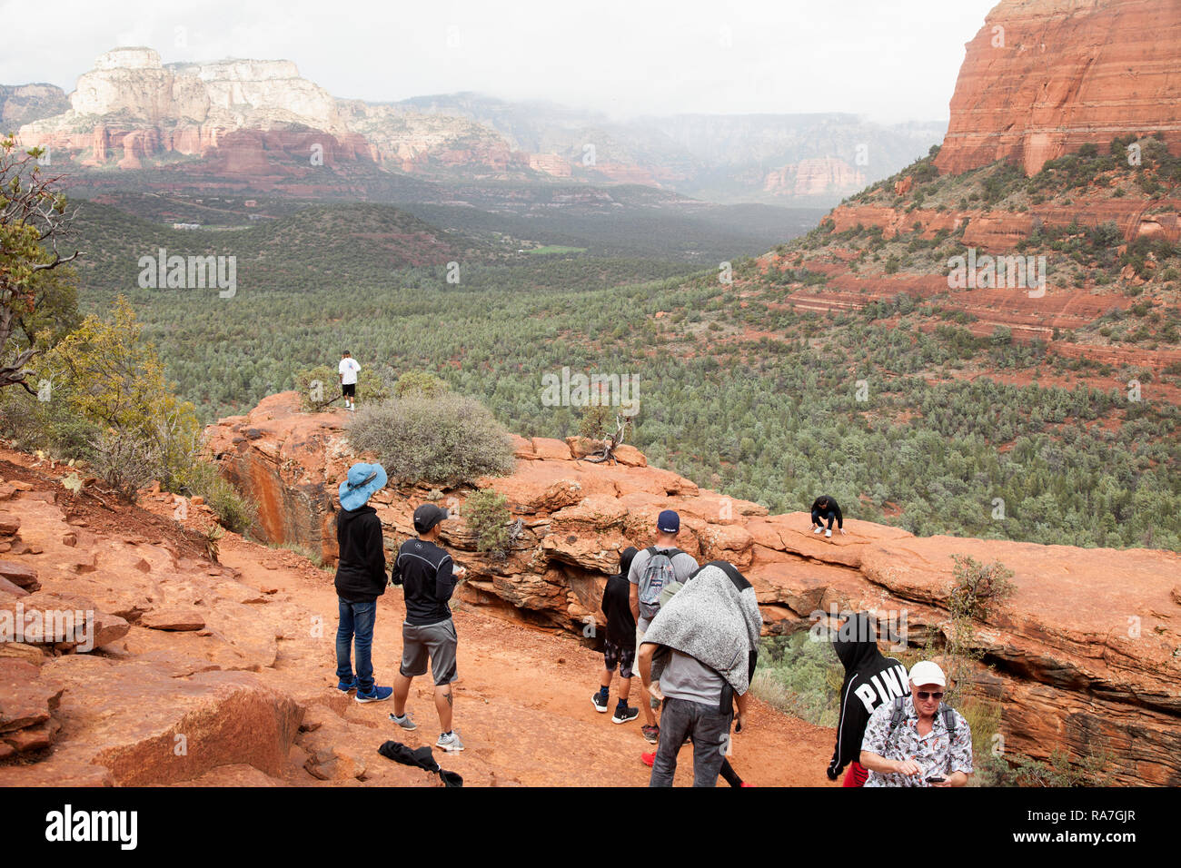 people walking along a natural stone arch calledDevils Bridge in Sedona, Arizona, USA Stock Photo