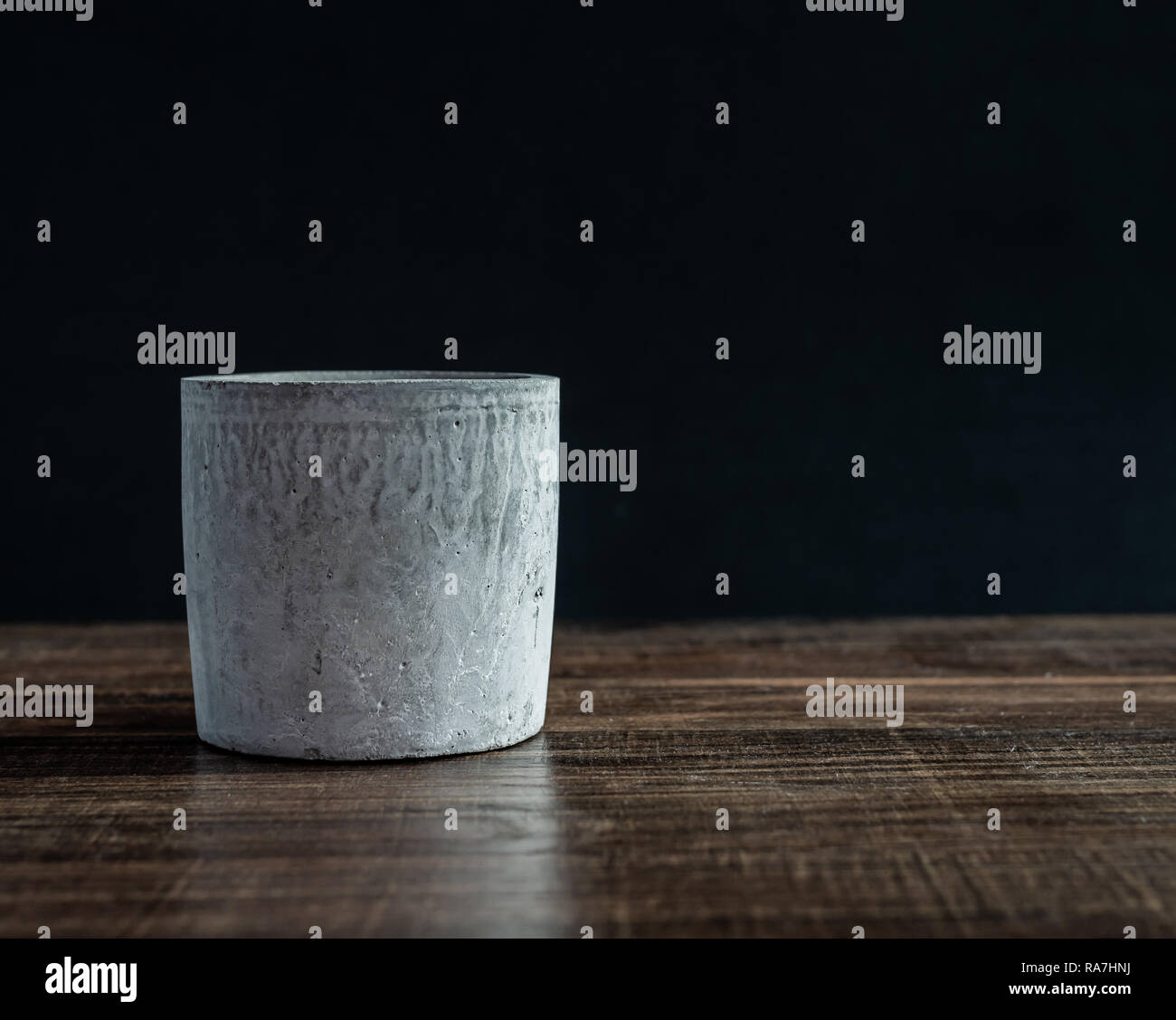 Empty modern concrete planter on wooden table isolated on black background with copy space. Stock Photo
