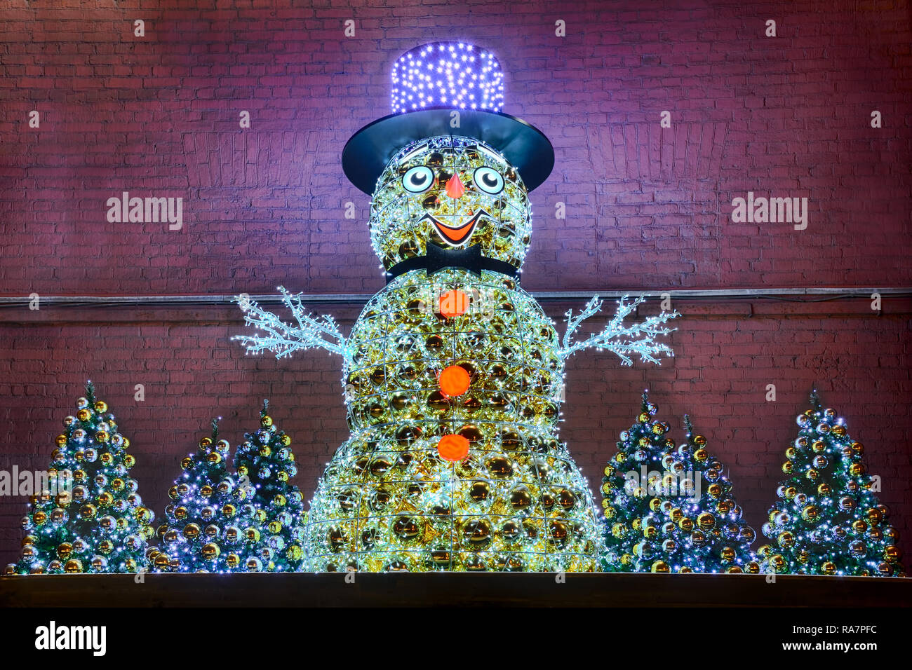 Snowman in Hat with Christmas Trees at the Wall of the Power Plant No 1 Stock Photo