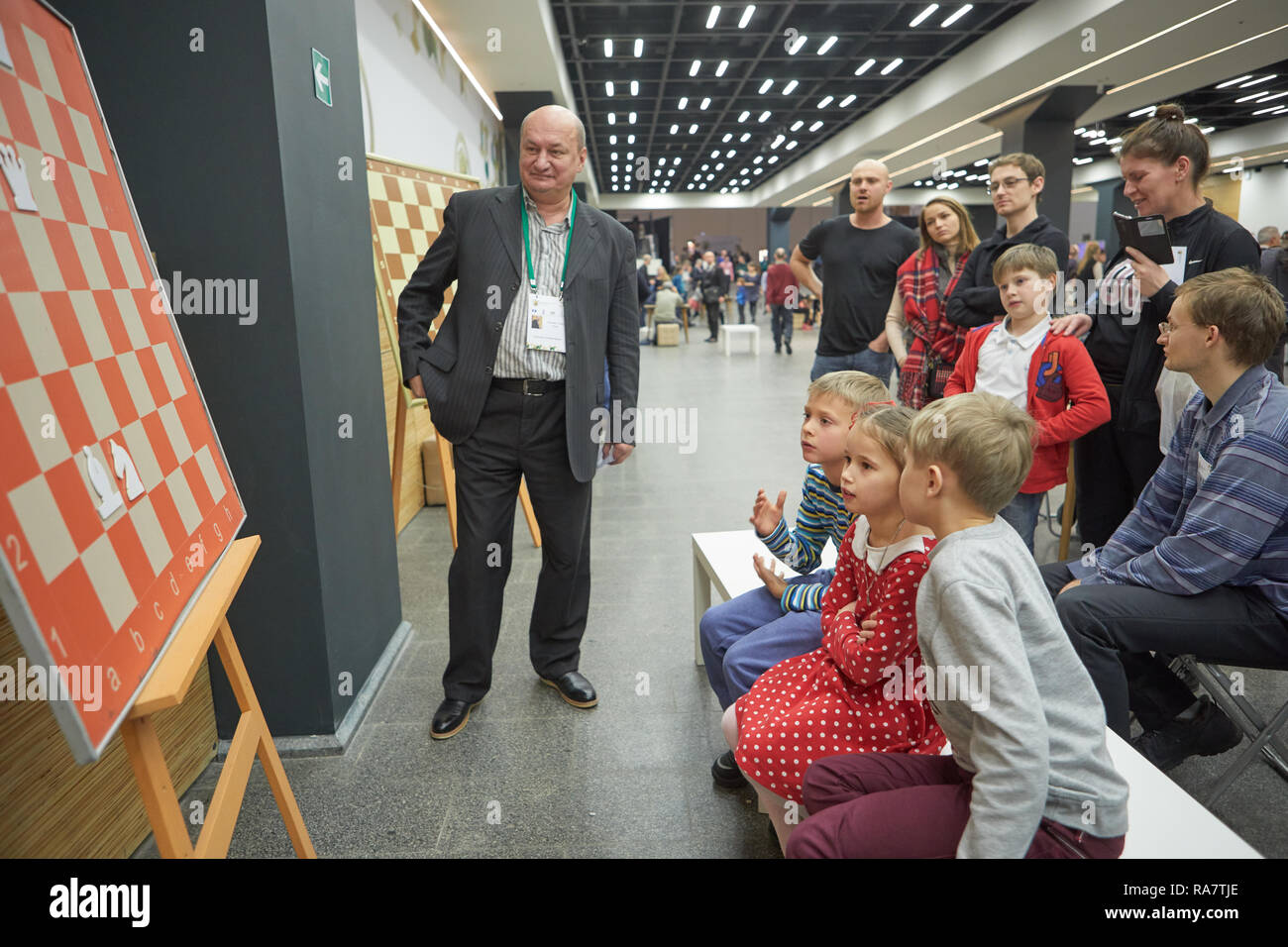 St. Petersburg, Russia - December 27, 2018: Three-time world champion for chess composition Oleg Pervakov gives a lesson to children during World Rapi Stock Photo