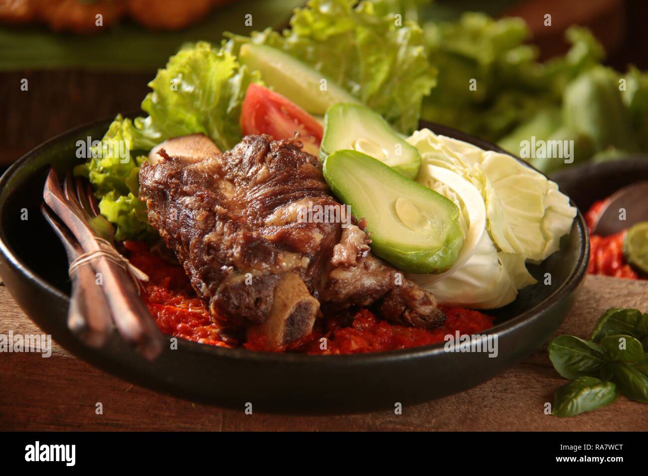 Iga Penyet. Javanese fried-then-smashed beef ribs served with red chili paste and fresh vegetables. Stock Photo