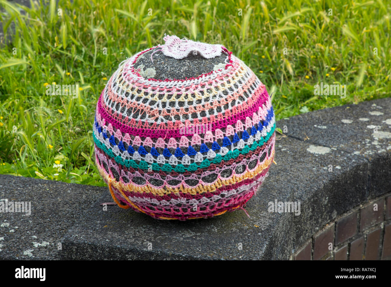 Stone ball on a wall, embroidered with wool, guerrilla knitting (composed of guerrilla - by span guerrilla for 'small war' - and English Knitting for  Stock Photo