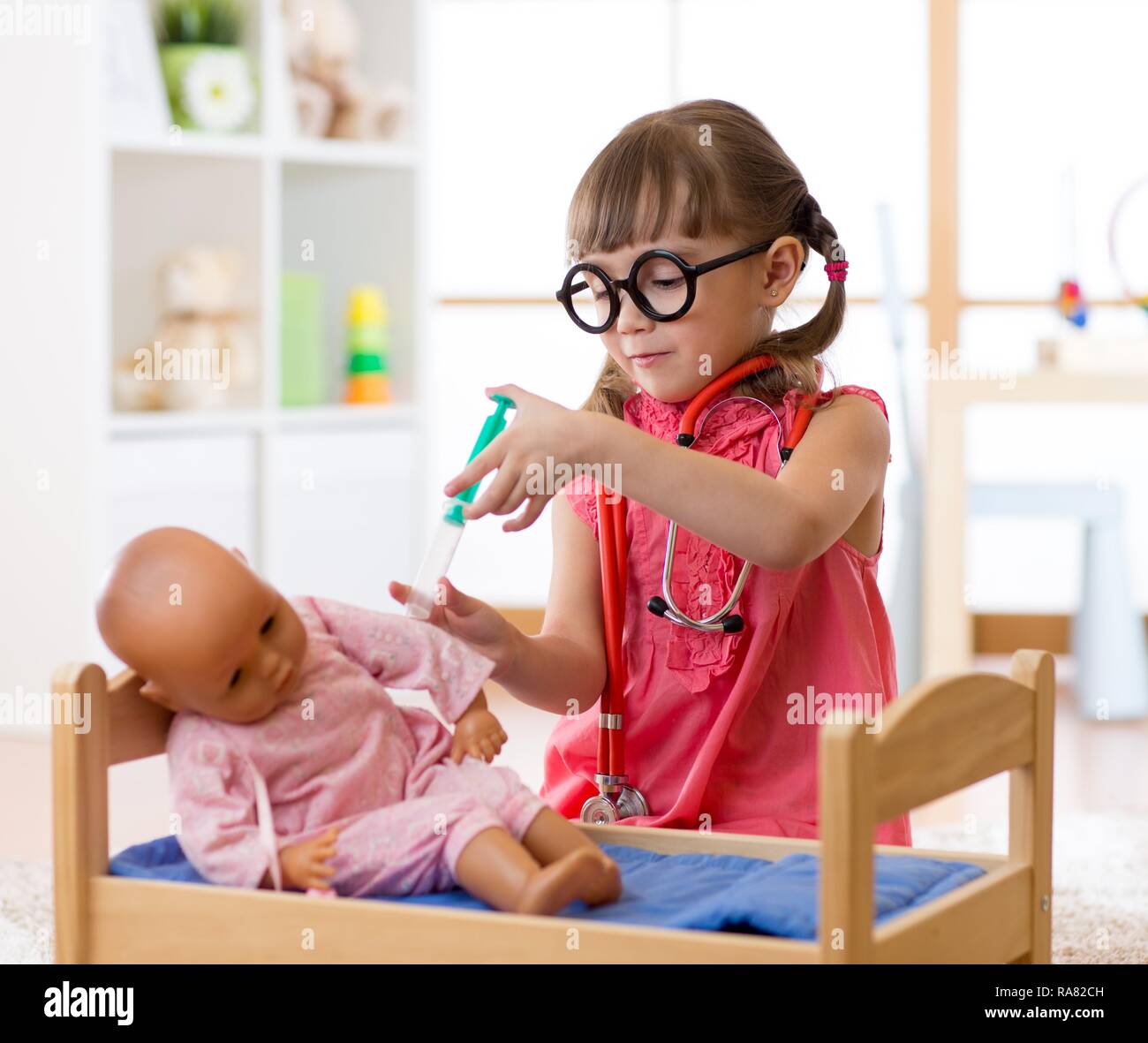 Child little girl playing with toy doll in nursery Stock Photo