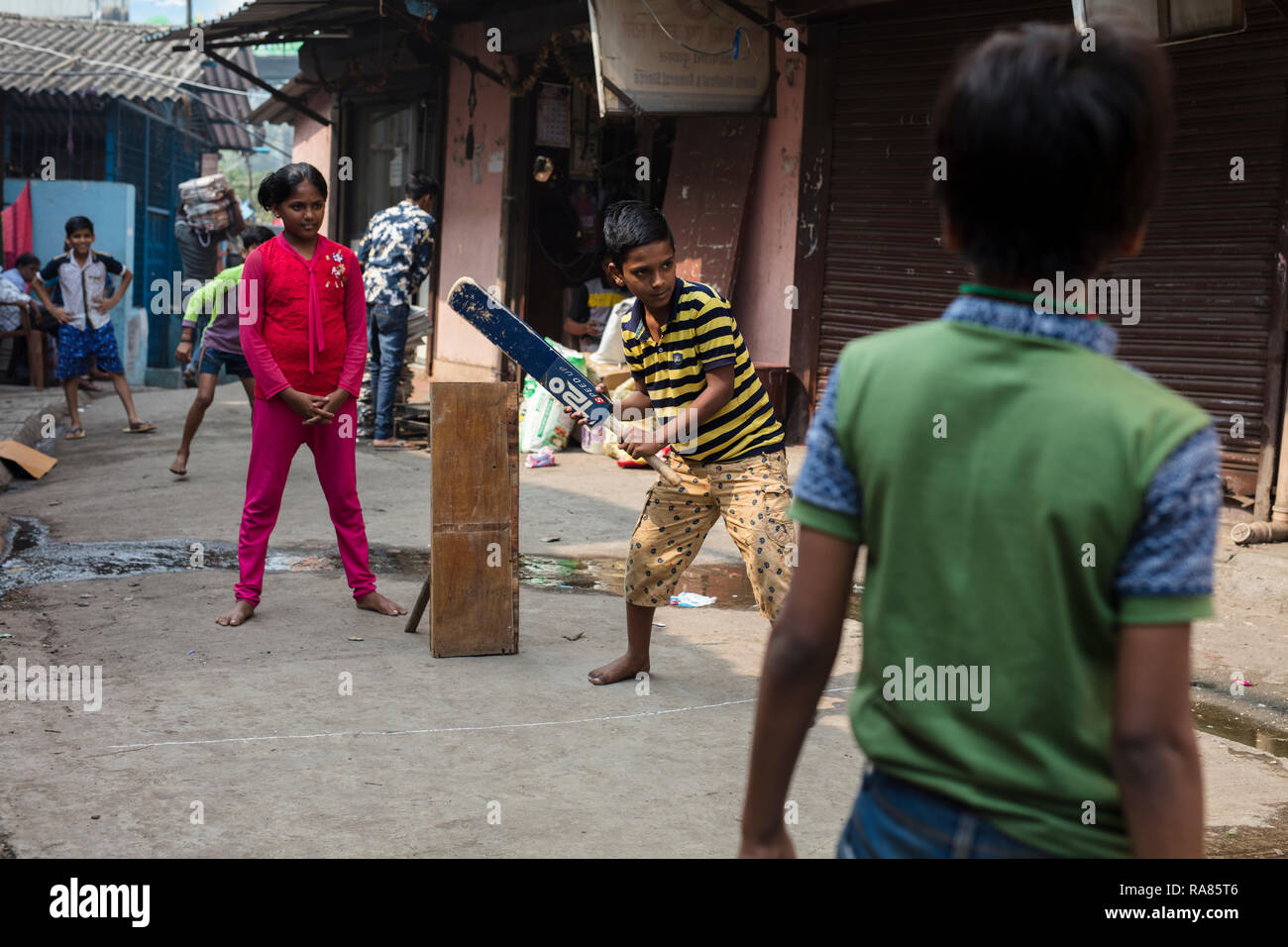 Mumbai, Maharashtra / India - December 12 2017: Children playing so-called „gully cricket“ in a small street in a slum in Mumbai. Stock Photo