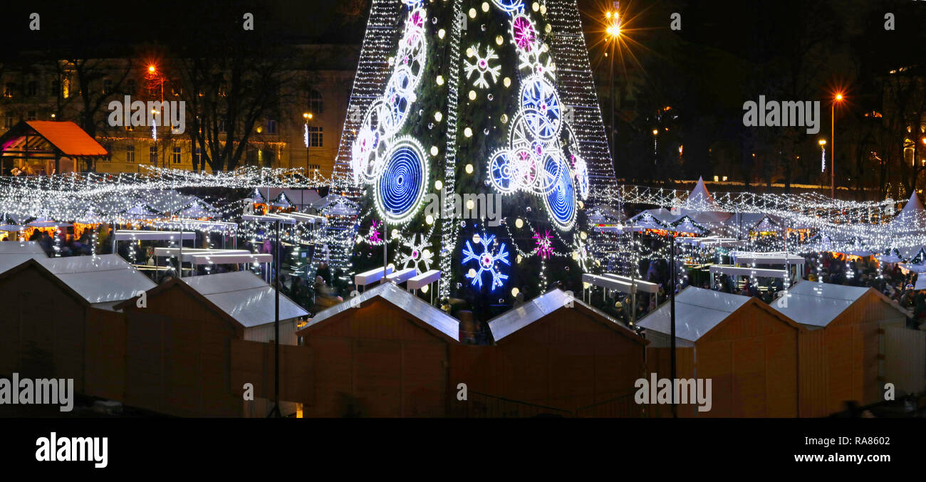 VILNIUS, LITHUANIA - DECEMBER 26, 2018: Christmas European  city square with  souvenir shops and decorated illuminate fir tree on  European old town.  Stock Photo