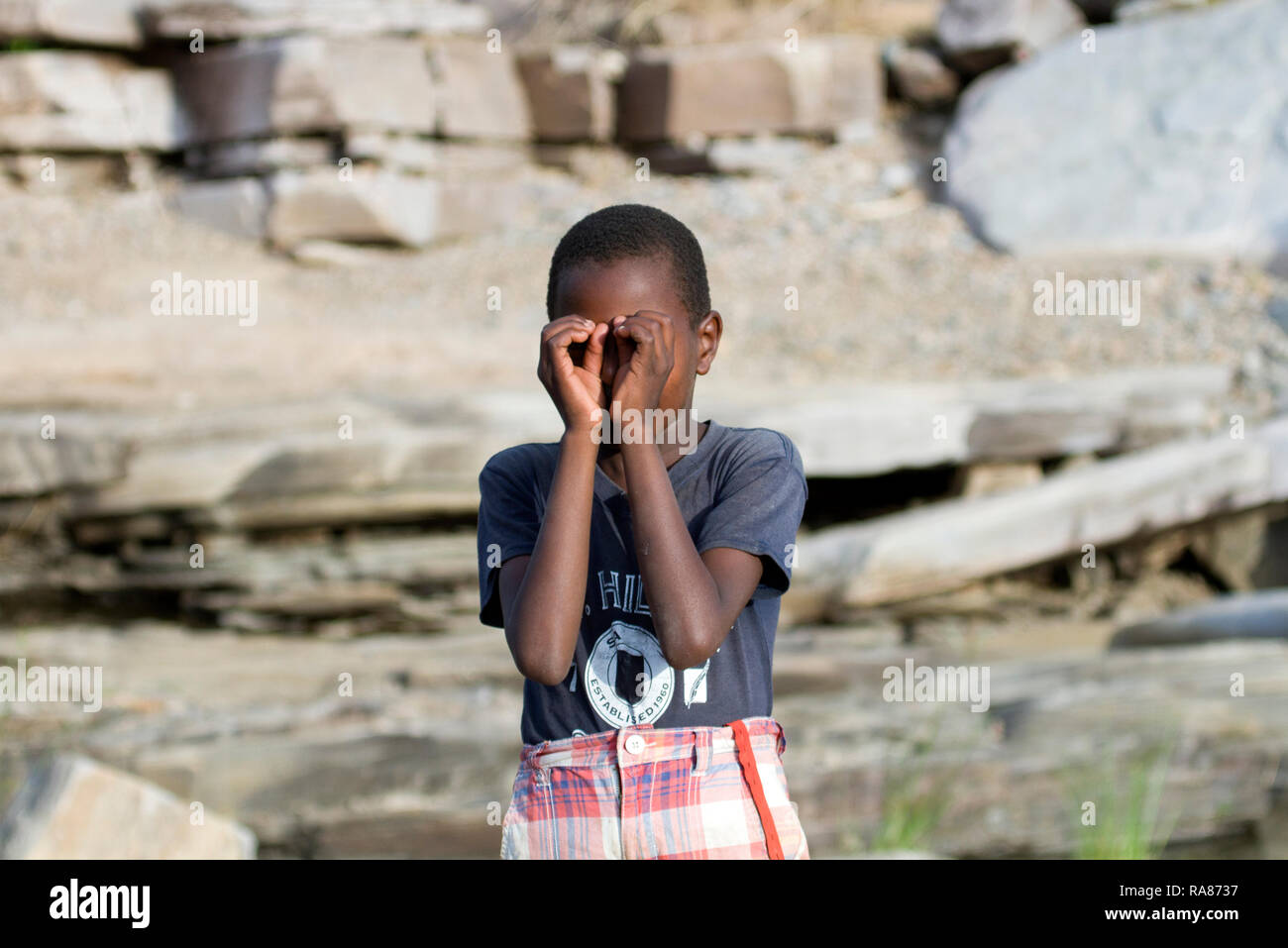 Young boy acting as he is holding a binocular at Masai village. Stock Photo