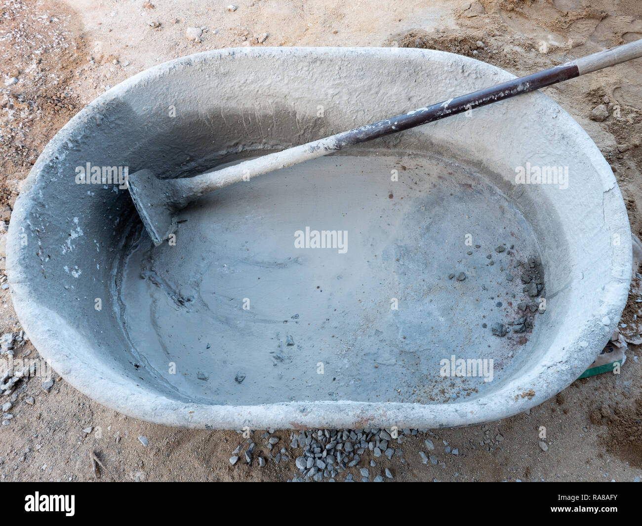 Large plastic bucket and metal hoe for mixing the cement mortar to