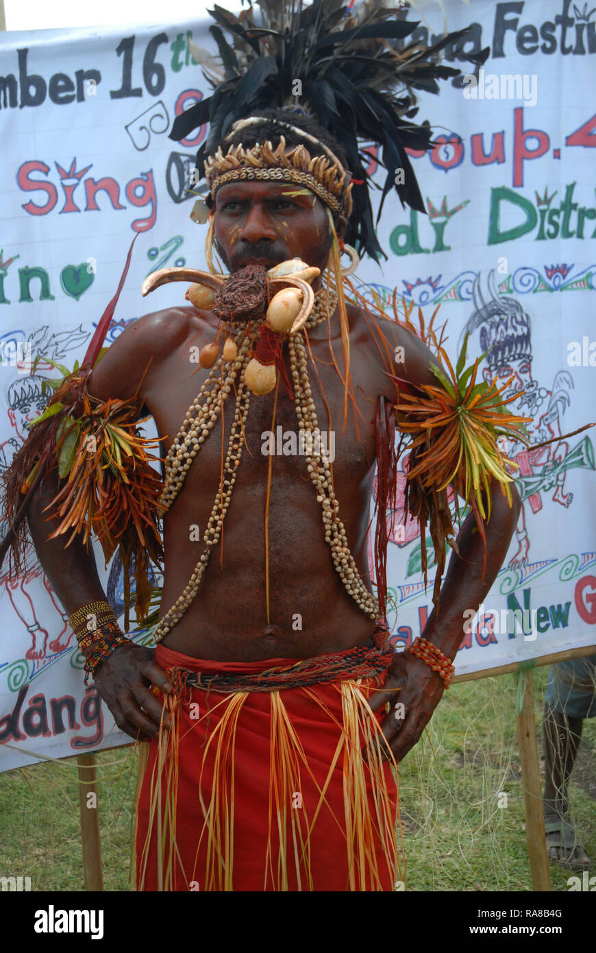 Colourfully dressed and face painted man wearing a neckless made from shells and hornbill beaks as part of a Sing Sing in Madang, Papua New Guinea. Stock Photo