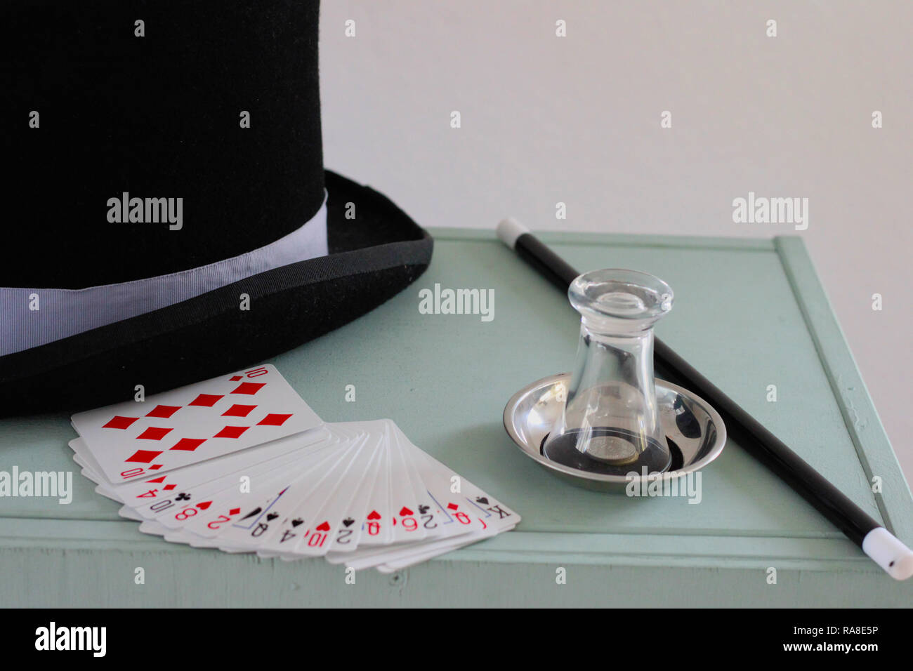 Magician's equipment on a painted chest. Stovepipe hat, cards, glass, coins, magic wand for magic tricks. Stock Photo
