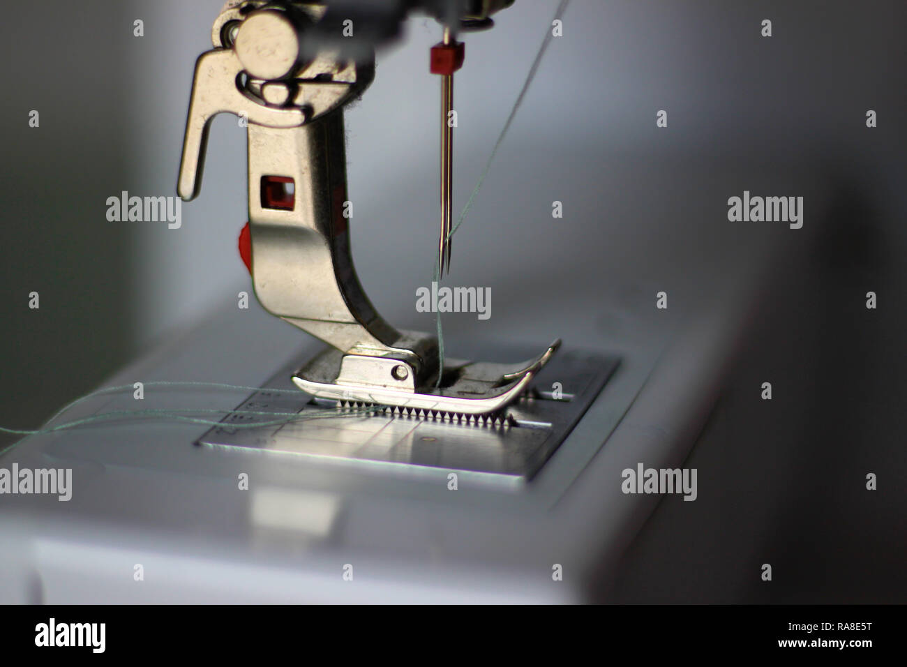 Close-up photo of a sewing machine. Pressing foot, double needle, light blue thread. Selectively focused. Stock Photo