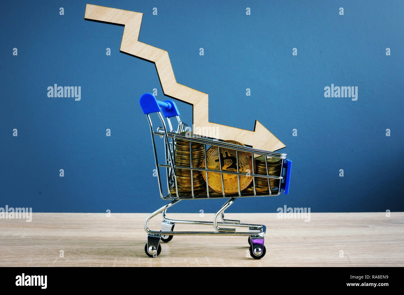 Crypto falling. BTC Bitcoin in shopping cart and arrow. Stock Photo