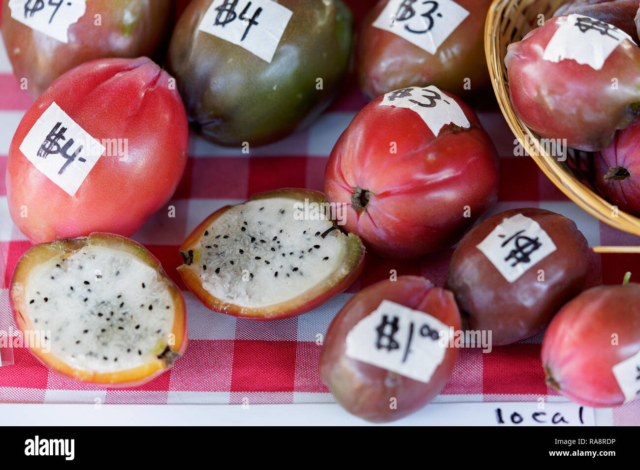 peruvuan cactus apples for sale on a table with a red and white checkered tablecloth at the market with price tags on the fruit Stock Photo