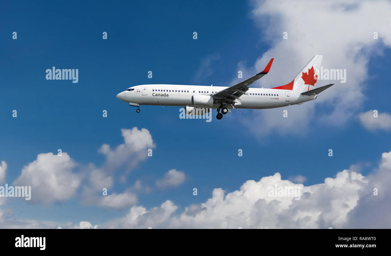 Passenger airplane landing at the airport with flag of Canada on tail. Commercial Canadian jet aircraft with blue cloudy sky in the background Stock Photo