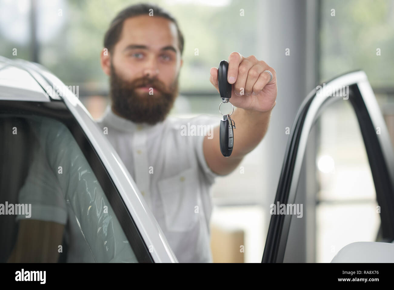 Close up of car keys. Windshield of white car with opened door