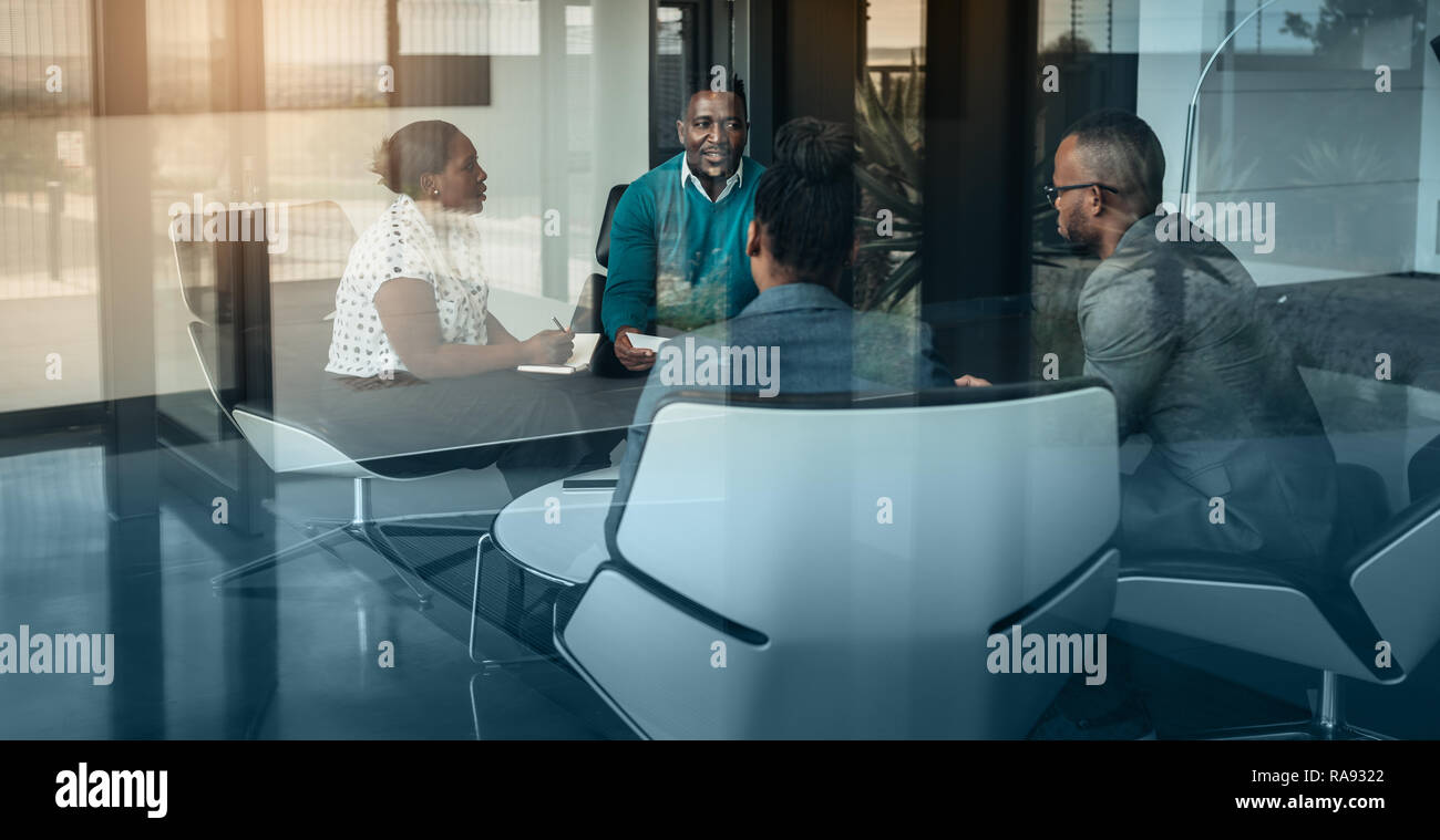 Team of african bussines people talking during an work meeting shot through a glass window, looking into the boardroom Stock Photo