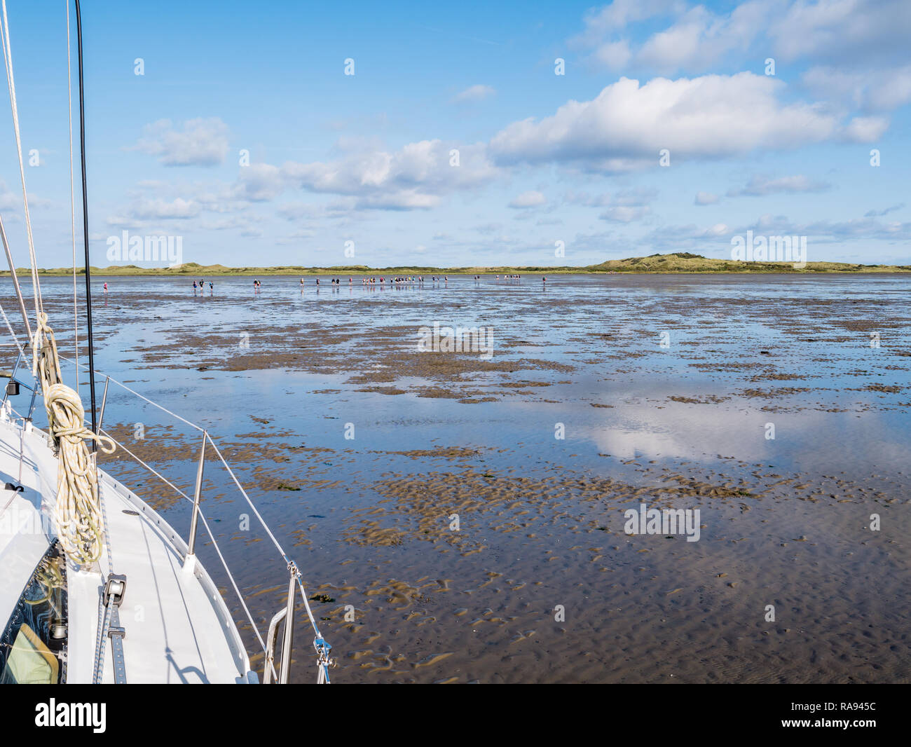 Group of people mud flat hiking on Wadden Sea at low tide from Friesland to West Frisian island Ameland, Netherlands Stock Photo