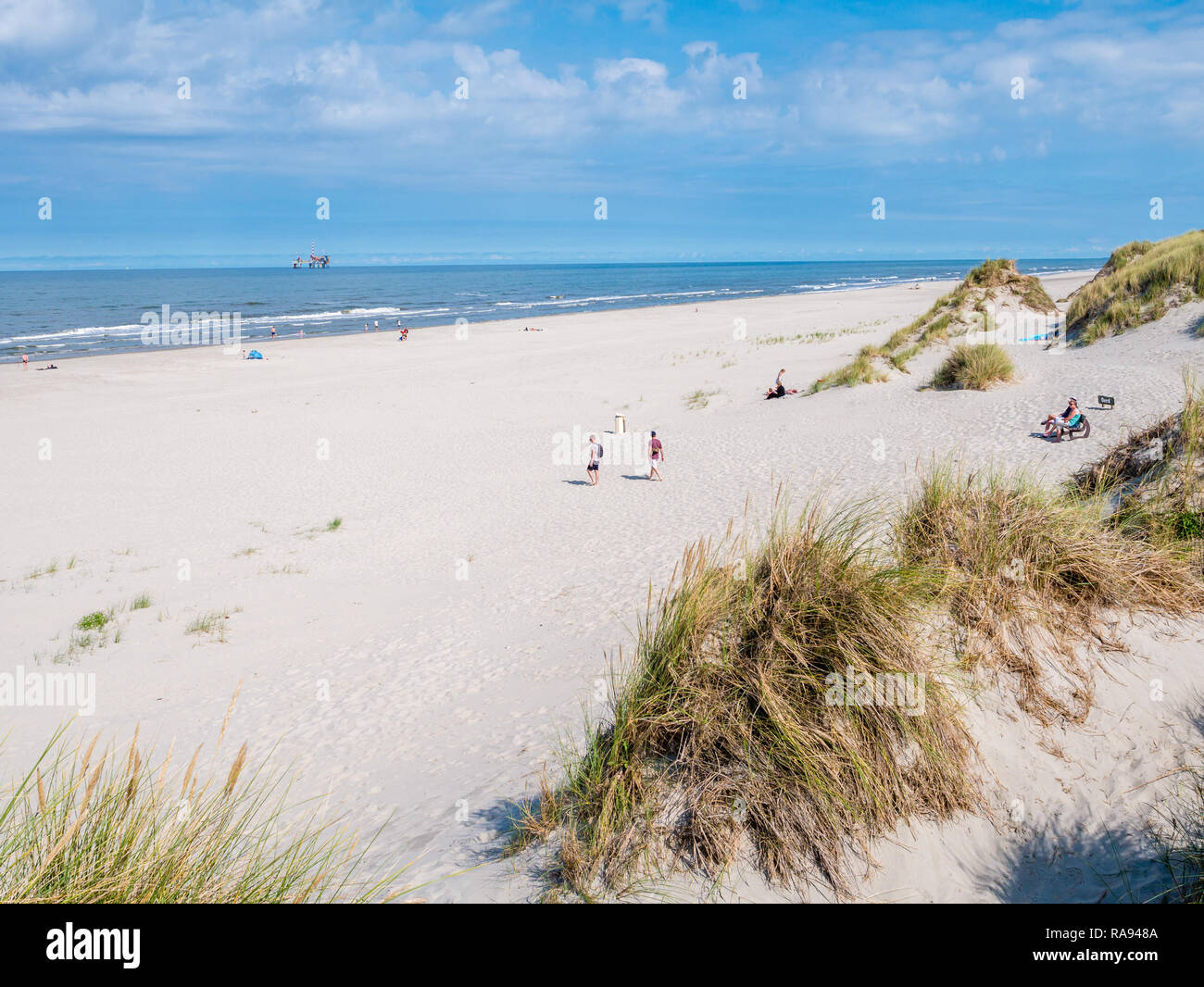 People on beach and North Sea with offshore drilling platform, West Frisian island Ameland, Friesland, Netherlands Stock Photo