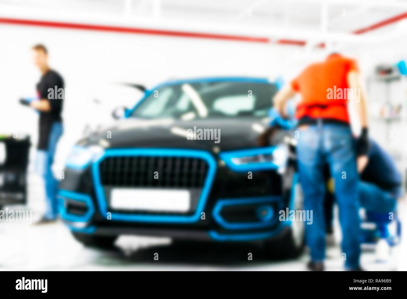 Blurred abstract image of man worker with car in a body shop. Blur car auto service. Car bokeh. Blurred background with car in garage. Vehicle mainten Stock Photo