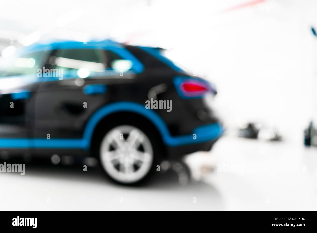 Blurred abstract image of man worker with car in a body shop. Blur car auto service. Car bokeh. Blurred background with car in garage. Vehicle mainten Stock Photo