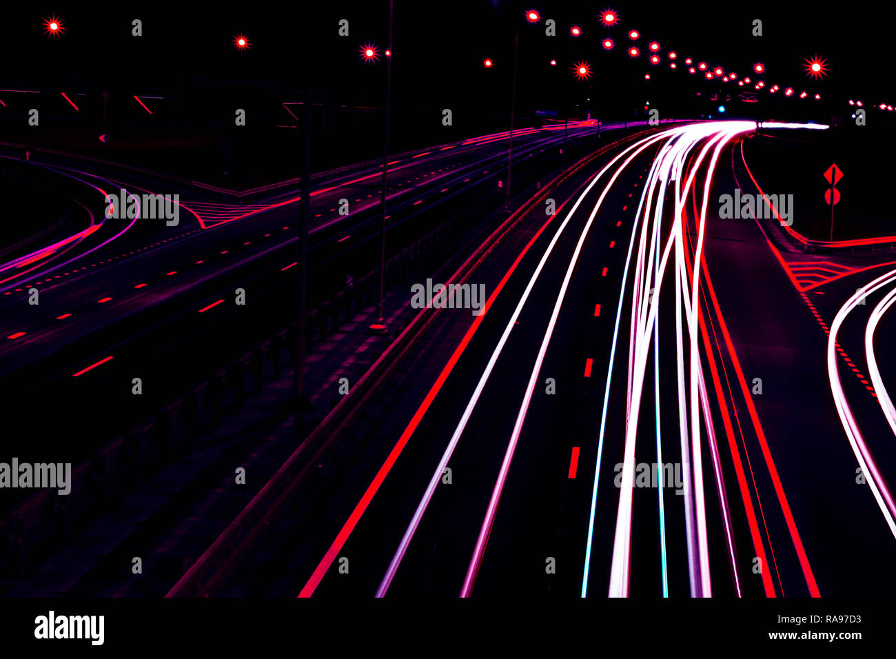 Cars light trails on a curved highway at night. Night traffic trails. Motion blur. Night city road with traffic headlight motion. Cityscape. Light up  Stock Photo