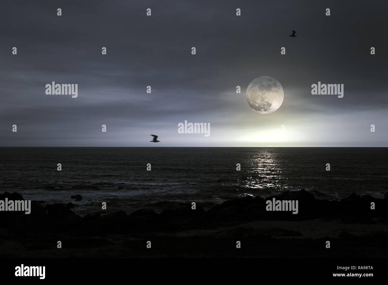 Moody full moon rise over Atlantic ocean Stock Photo