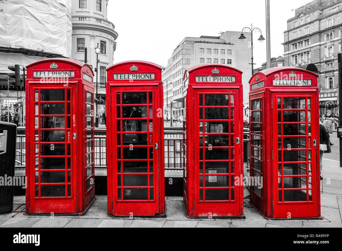 Four traditional British red telephone boxes are standing on the street.   Booth are isolated in a black and white picture Stock Photo