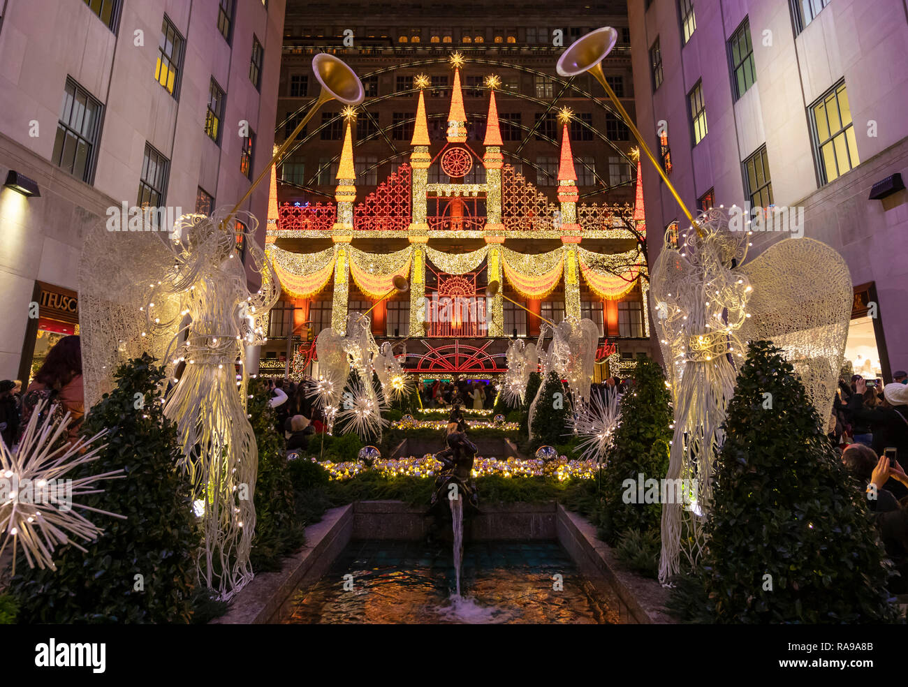 A colorful Christmas display on department store building at Rockefeller Center surrounded by the angels and visitors.. Stock Photo