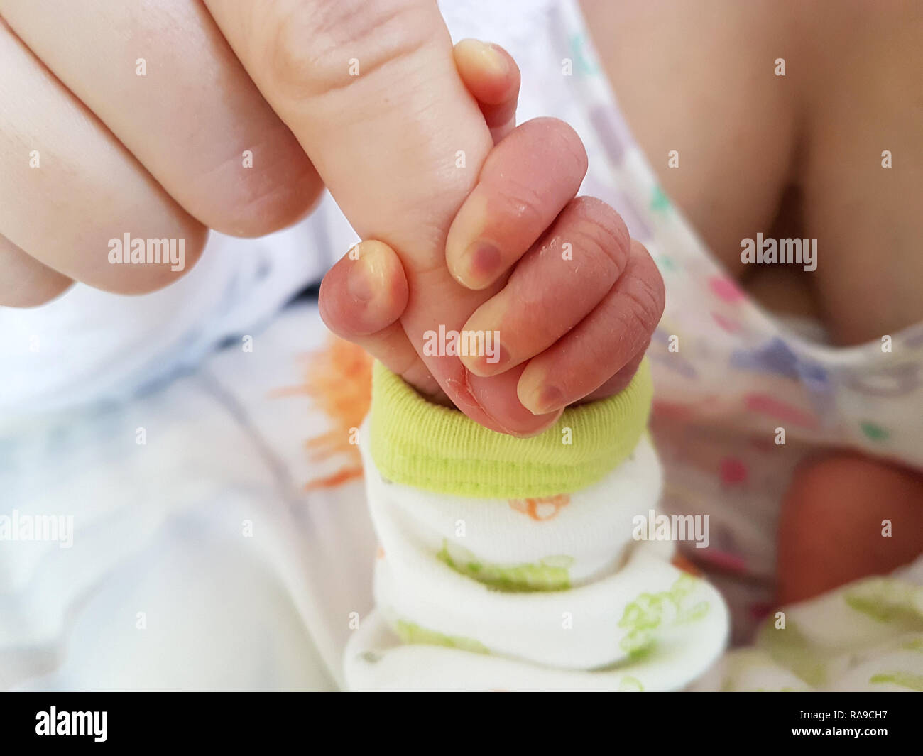Baby hand wrapped around finger Stock Photo