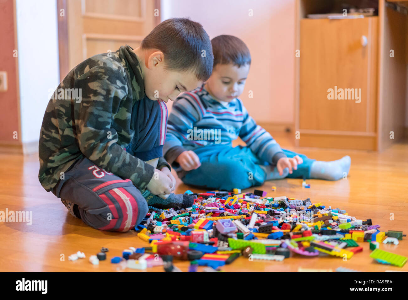 Two children playing with lots of colorful plastic blocks constructor ...