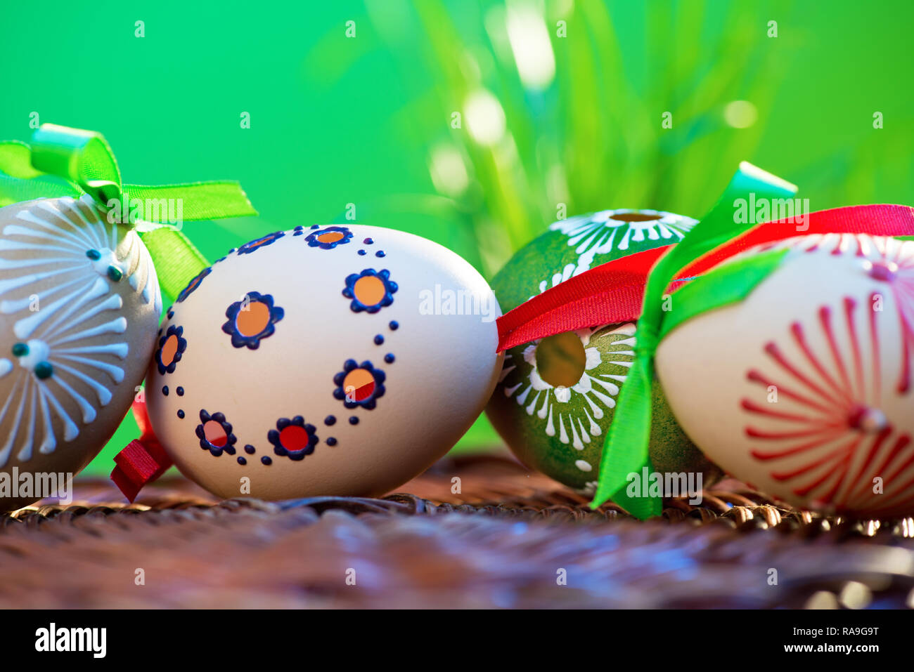 Painted easter eggs in the wicker basket in the grass. Stock Photo